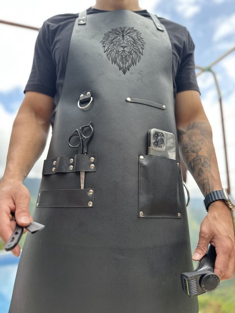 Delantal de barbero negro con tijeras en el porta tijeras y un celular en el bolsillo
