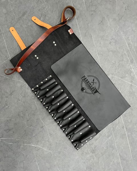 Estuche de cuchillos de cuero negro abierto, con sus bolsillos y un logo grabado