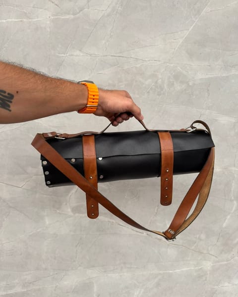 Estuche de cuchillos de cuero negro en la mano, con correas miel