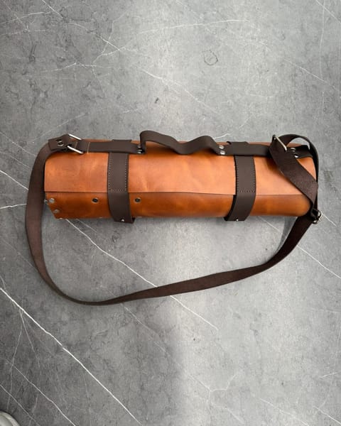 Estuche de cuchillos de cuero miel enrollado, con correas café y su correa para el hombro