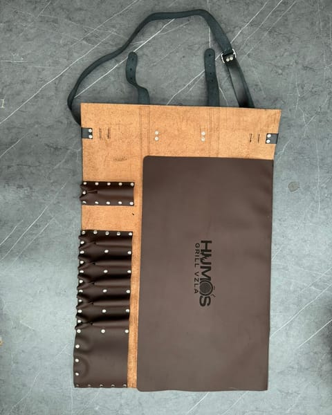Estuche de cuchillos abierto, con los bolsillos y la tapa en cuero café y un logo grabado