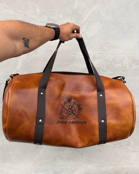 Maleta de cuero miel con correas café y un diseño con un nombre grabado