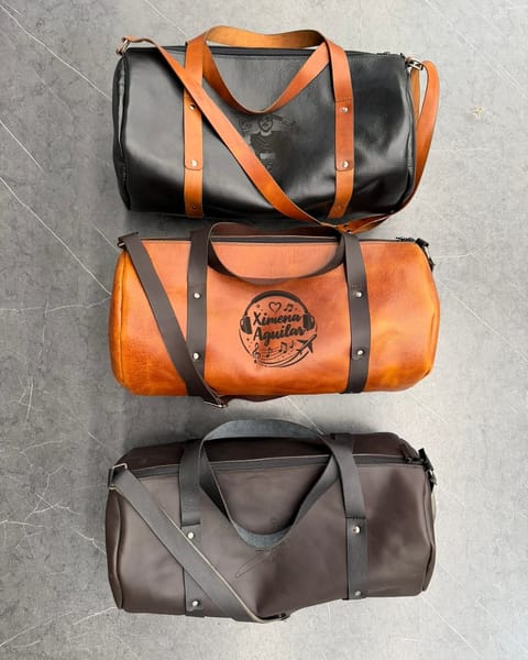 Tres maletas de cuero: negro con correas miel, miel y café, con diseños grabados