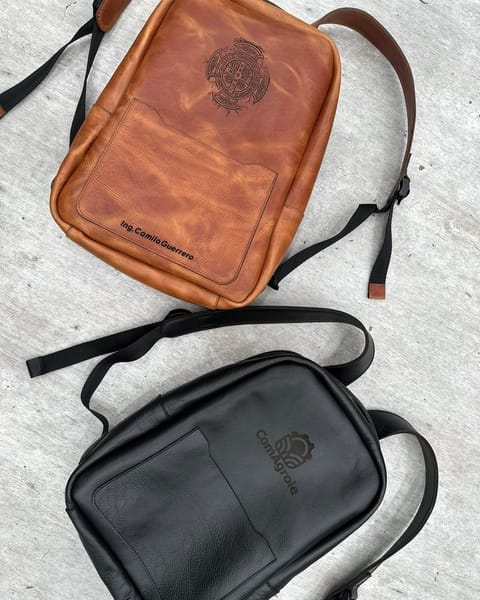 Maletines de cuero miel y negro de cerca, con un diseño, un nombre y un logo grabados