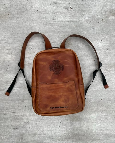 Maletín de cuero miel con un logo y un nombre grabados, de frente