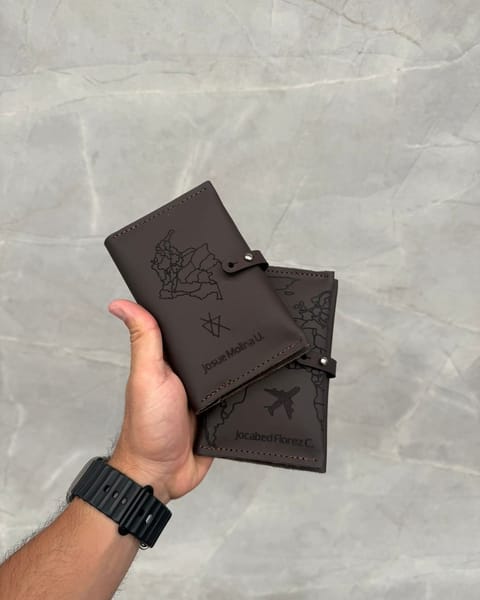 Dos portapasaportes dobles de cuero café con diseños de viaje grabados