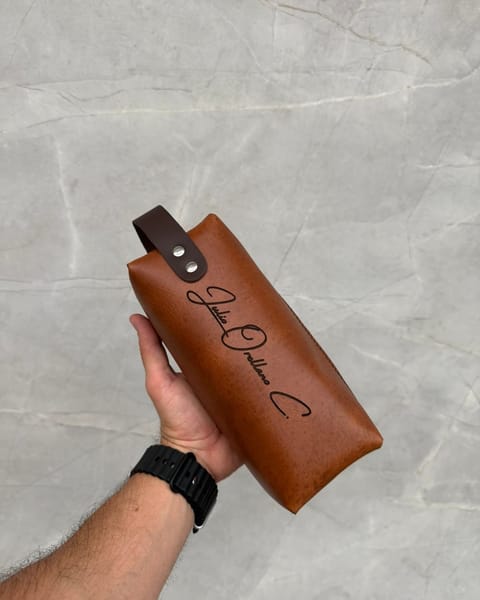 Travel dopp de cuero miel en la mano, con un nombre grabado
